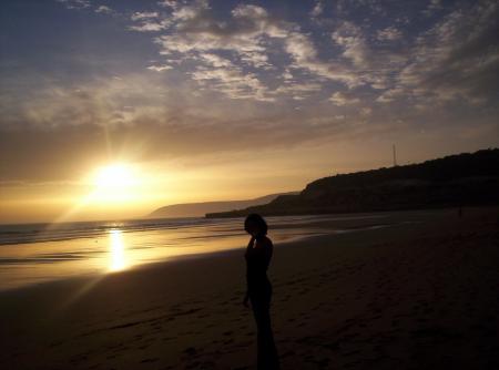 Maman contemplant le coucher du soleil sur la plage de Taghazoute.